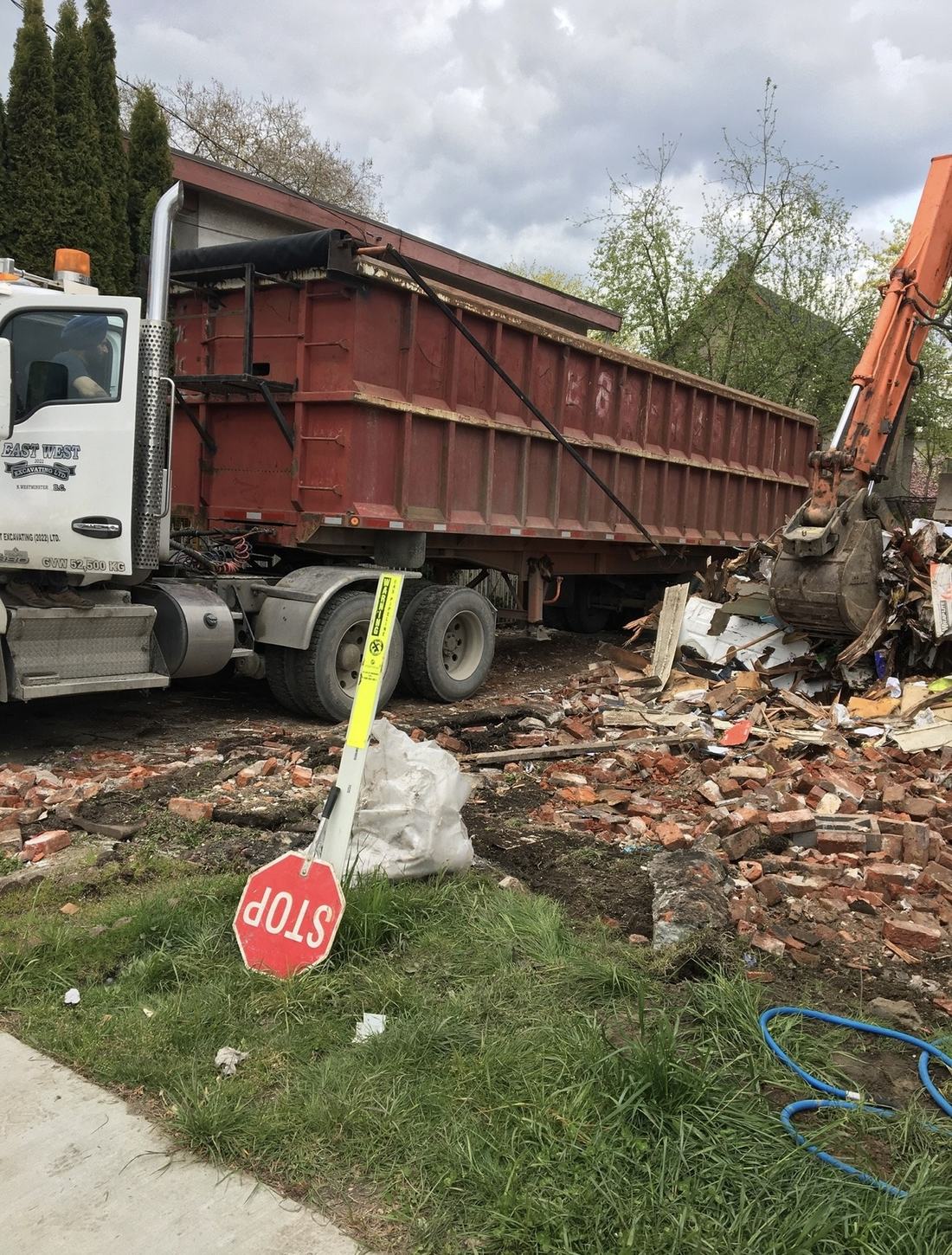 Dump truck and excavator clearing demolition debris on a residential lot
