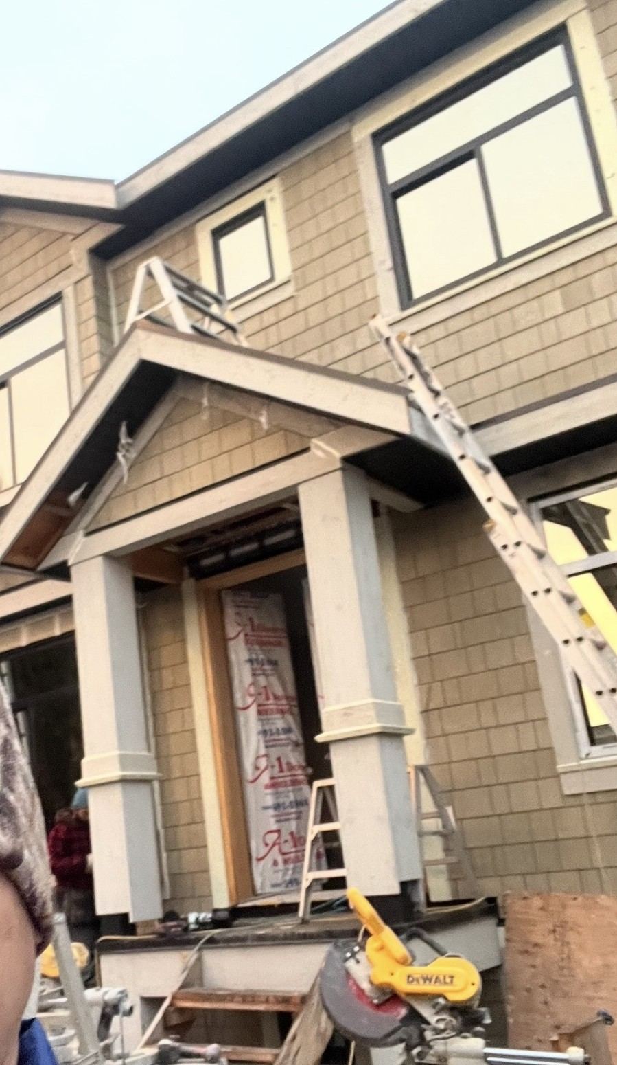 Framing stage of a custom home with entry portico structure and ladders