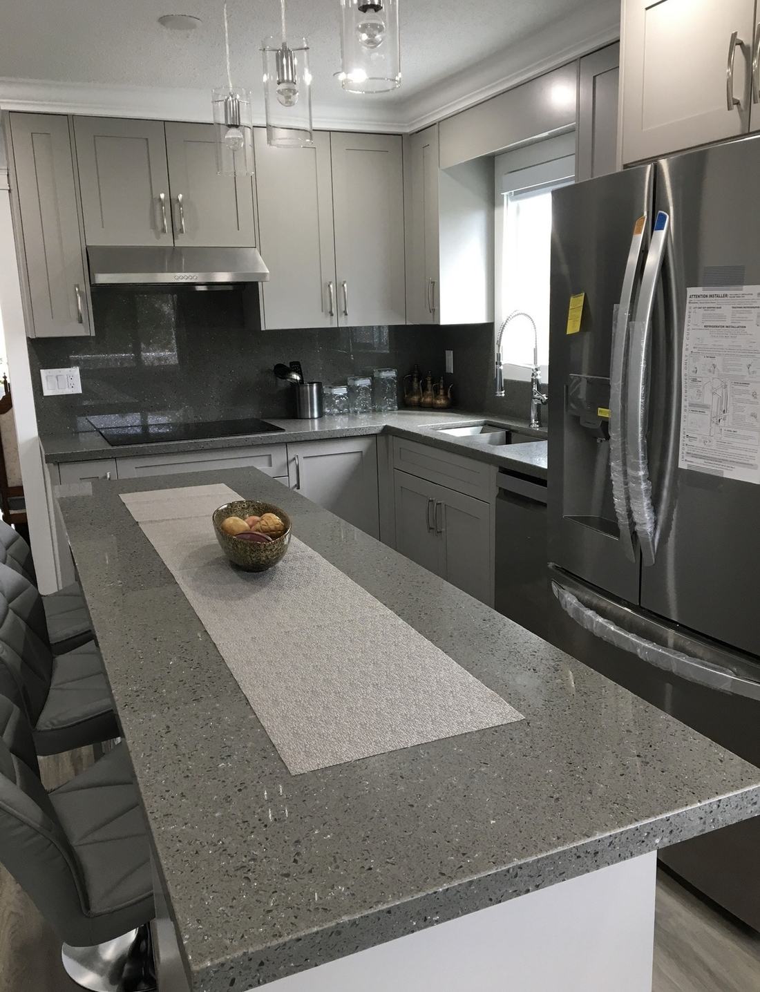Finished kitchen with quartz island countertop and grey cabinetry