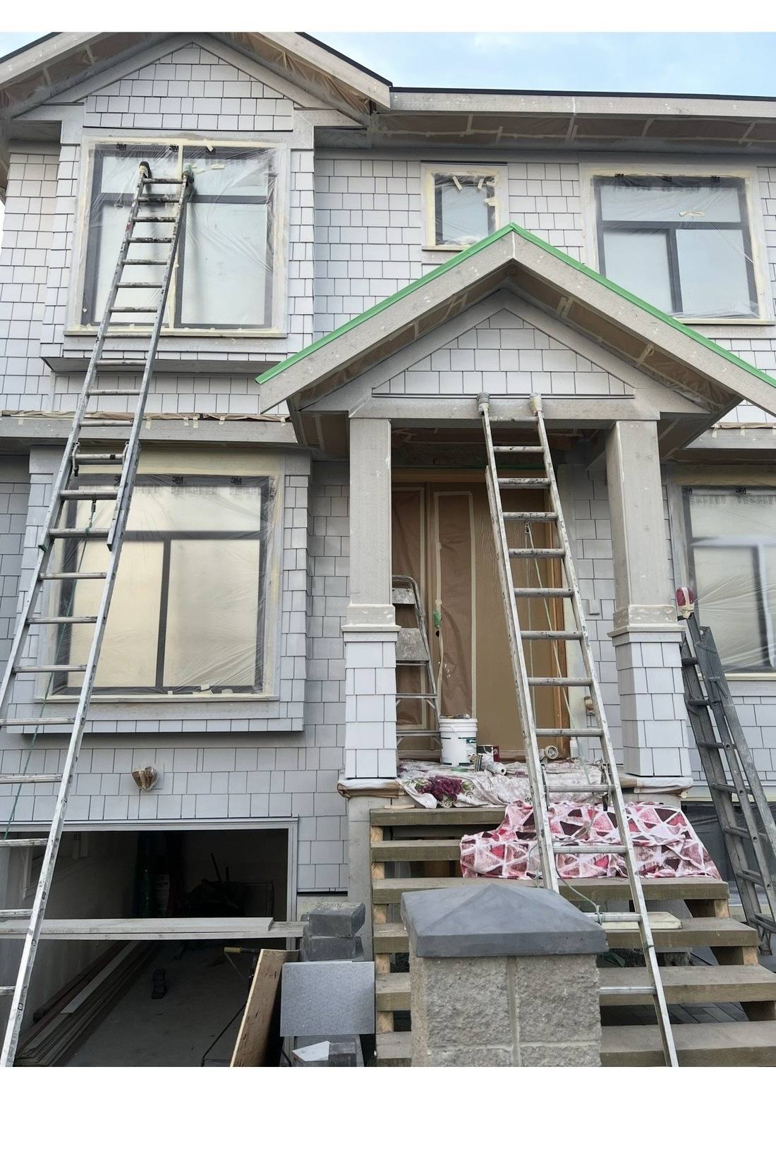 Riley Park home during exterior painting preparation, windows masked, ladders in place